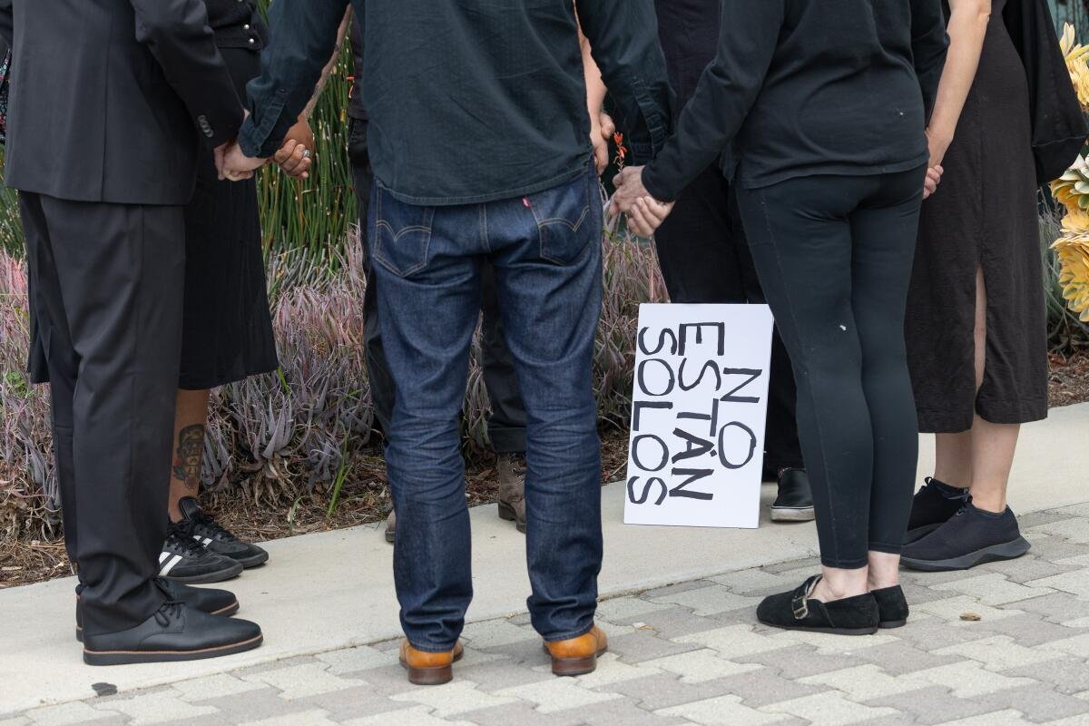 A small group of people stand in a circle, holding hands, as they pray.