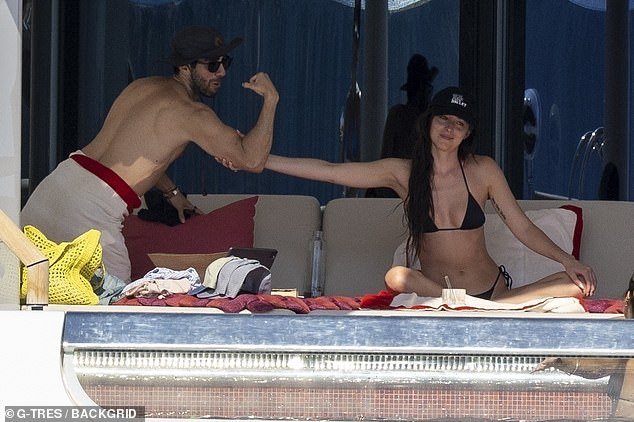 He went shirtless with a towel easily wrapped around his waist and leaned over to Dakota who playfully touched his arm bicep